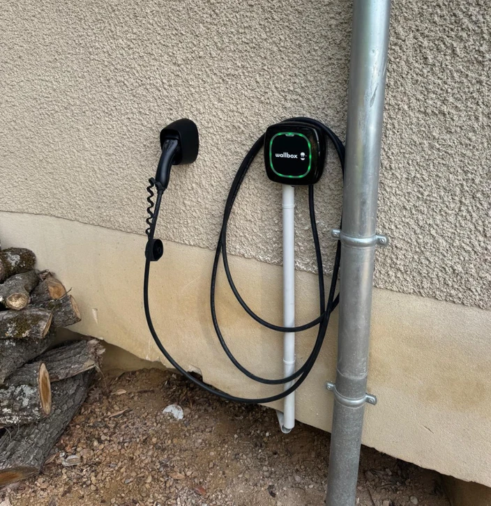 Extérieur, borne de recharge électrique ChargePoint installée dans un environnement résidentiel avec végétation en arrière-plan
